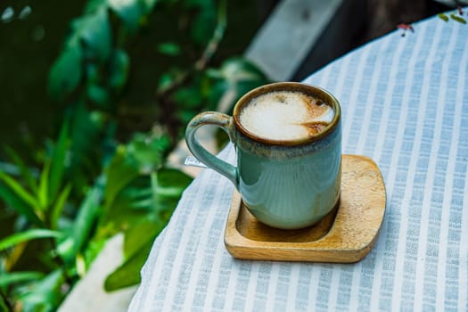 Cup of coffee latte with heart shape on old wooden background in the morning sunlight
