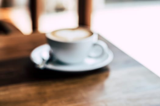 Cup of coffee latte with heart shape on old wooden background in the morning sunlight