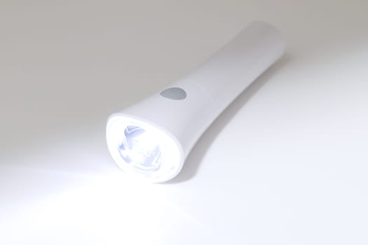 Electric led flashlight and ray of light on white background