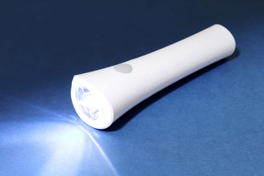 Electric led flashlight and ray of light on dark background