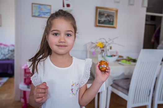 Portrait of adorable little girl with colorful Easter eggs at home, Holiday day