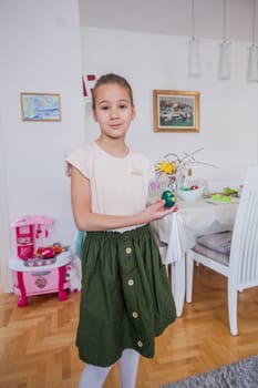 Portrait of adorable little girl with colorful Easter eggs at home, Holiday day
