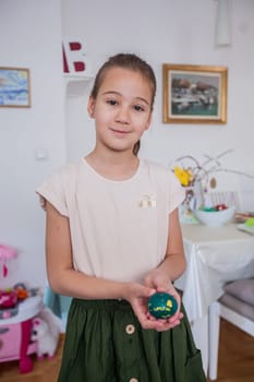 Portrait of adorable little girl with colorful Easter eggs at home, Holiday day