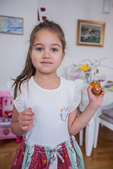 Portrait of adorable little girl with colorful Easter eggs at home, Holiday day