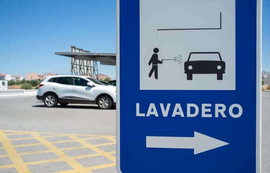 Car wash area sign. Sport utility vehicle at background. Spanish language