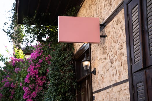 Horizontal front view of empty pink square signage on a building with classical rustic architecture