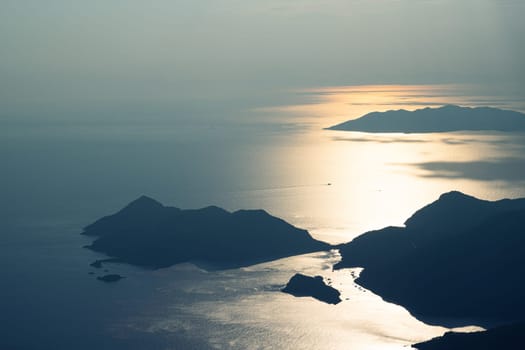 beautiful aerial panorama from the Babadag peak of high mountains rising up over the Mediterranean sea at sunset near Oludeniz Blue Lagoon coast in Turkey during summer