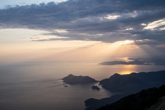 beautiful aerial panorama from the Babadag peak of high mountains rising up over the Mediterranean sea at sunset near Oludeniz Blue Lagoon coast in Turkey during summer