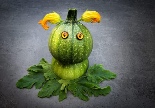 Funny round zucchini with googly eyes over dark background