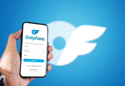 London, UK, August 2021  a hand holds a mobile phone with the OnlyFans registration form on the screen and the logo blurred in the background.