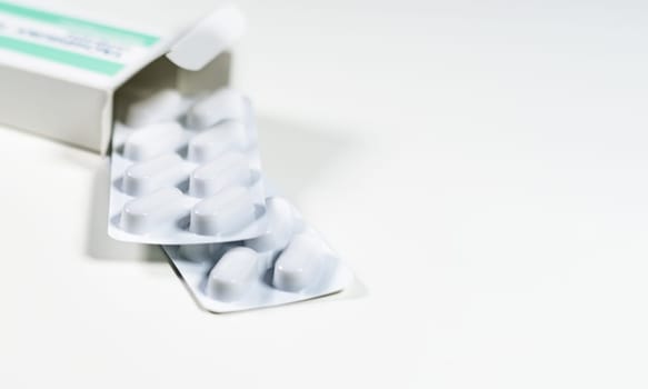White blister with pills in a green and white box isolated on a white background. Chemistry and medicine. Healthcare and cure concept.