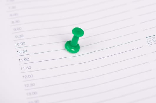 Green pin needle in an empty calendar page, saving the date