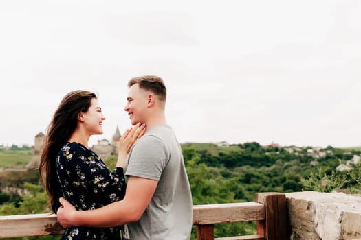 Young Caucasian loving mature couple relaxing during outdoor activities, smiling, hugging and kissing. Walk through route on national park. Two tourists guy and girl joyful walk outside the city