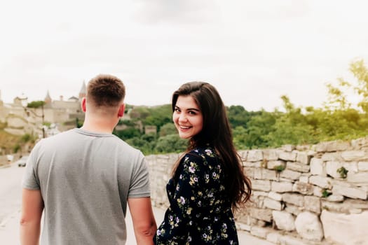 Young Caucasian loving mature couple relaxing during outdoor activities, smiling, hugging and kissing. Walk through route on national park. Two tourists guy and girl joyful walk outside the city