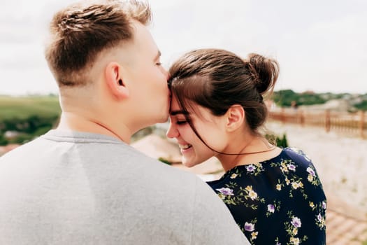 Young Caucasian loving mature couple relaxing during outdoor activities, smiling, hugging and kissing. Walk through route on national park. Two tourists guy and girl joyful walk outside the city