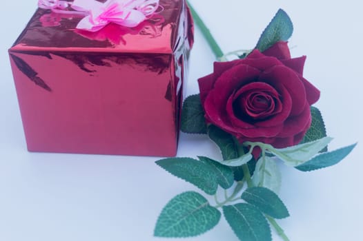 Gift box and a red rose in white background. Low angle view. Copy Space.