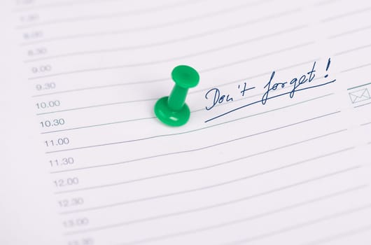 The words don´t forget are standing on a calender page, green pin needle