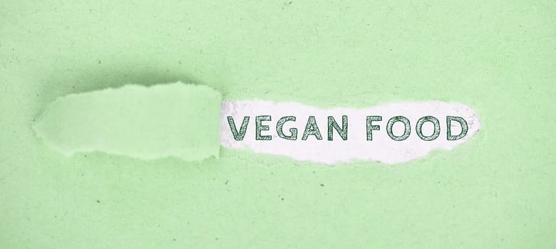 The words vegan food standing on a green ripped up paper