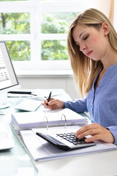 Young Businesswoman Calculating Bill With Computer And Laptop On Desk