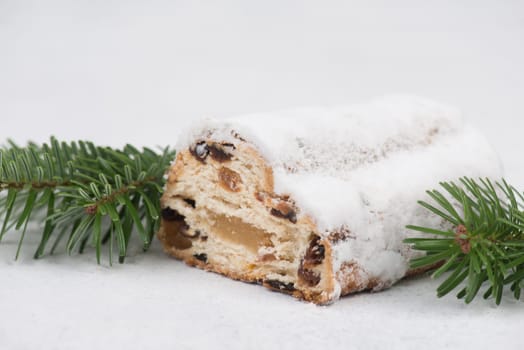 Christstollen, traditonal christmas cake with nuts, raisons, marzipan on a white background, empty space for text