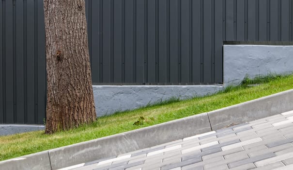 A long descent covered with gray paving slabs. The ramp is paved with concrete tiles. Wheelchair and bicycle accessibility concept