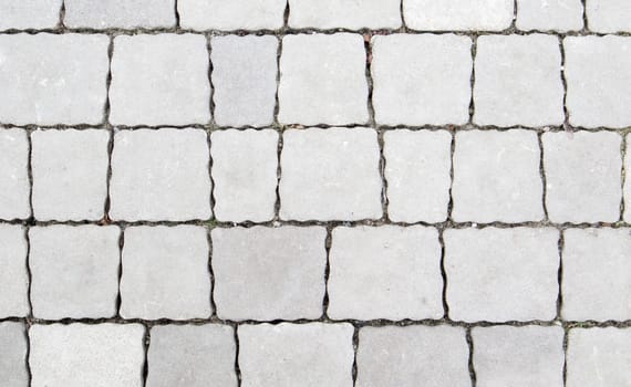 Concrete or paved newly laid gray paving slabs or stones for floors or walkways. Concrete paving slabs in the backyard or road paving. Garden brick path in the courtyard on a sandy foundation