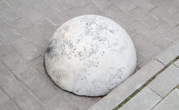 Round concrete road parking block in the shape of a hemisphere to prevent cars from parking here. Artificial obstacle for traffic and parking. Anti-parking barrier stone in the city