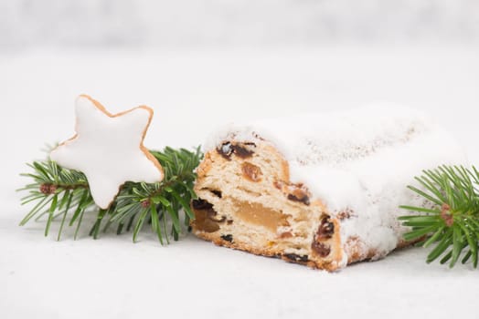 Christstollen, traditonal christmas cake with nuts, raisons, marzipan on a white background, empty space for text