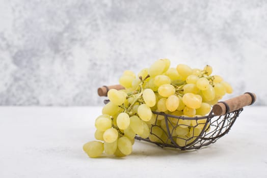 Grapes in a basket on a textured background, empty space for text