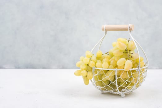 Grapes in a basket on a textured background, empty space for text