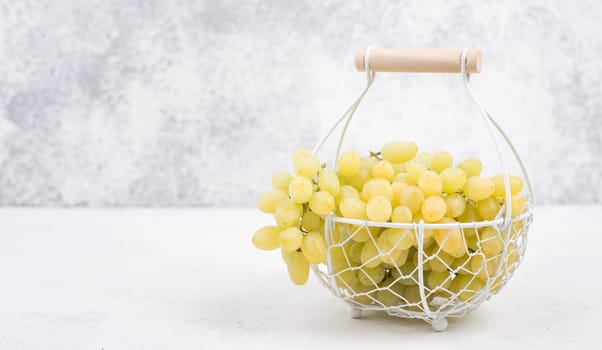 Grapes in a basket on a textured background, empty space for text