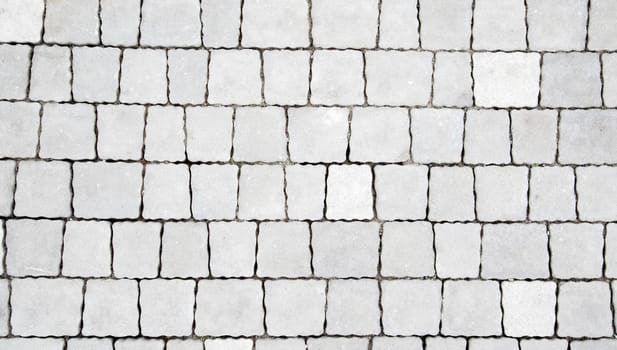 Concrete or paved newly laid gray paving slabs or stones for floors or walkways. Concrete paving slabs in the backyard or road paving. Garden brick path in the courtyard on a sandy foundation