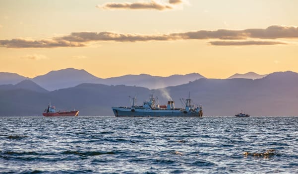 The large fishing vessel on the background of hills and volcanoes in Kamchatka Peninsula