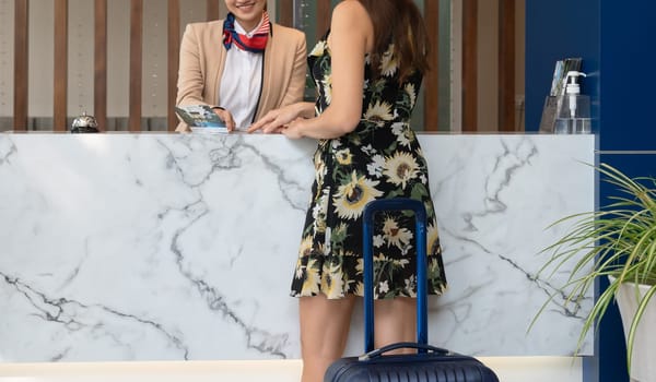 Woman receptionist giving hotel information service to female guest upon arrival