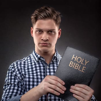 Young christian man showing showing with determination a Holy Bible  (concept against temptation by God's Word)