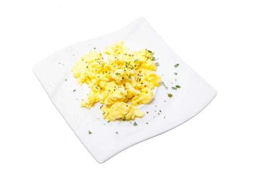 Breakfast with scrambled eggs. Plate with scrambled eggs on a light plate for white ground.