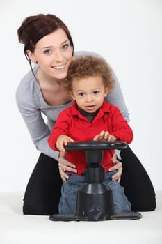 Woman and child playing with a toy steering wheel