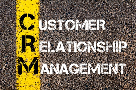 Acronym CRM - Customer Relationship Management. Business Conceptual image with yellow paint line on the road over asphalt stone background.