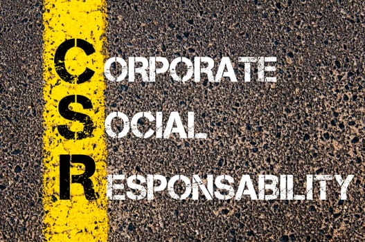 Acronym CSR - Corporate Social Responsability. Business Conceptual image with yellow paint line on the road over asphalt stone background.