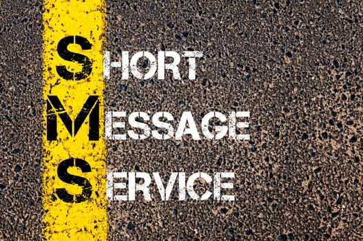Acronym SMS - Short Message Service. Business Conceptual image with yellow paint line on the road over asphalt stone background.