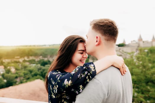 Young Caucasian loving mature couple relaxing during outdoor activities, smiling, hugging and kissing. Walk through route on national park. Two tourists guy and girl joyful walk outside the city