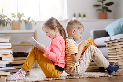 Two children sitting on the floor in the room and reading books- Concept of the family relationship, education and hobby.