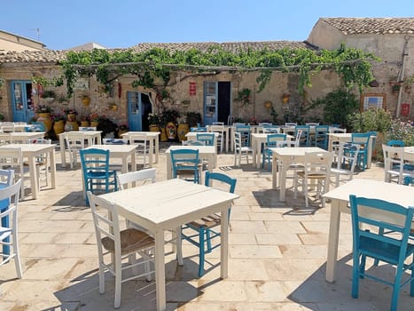 Tables and chairs in the square at Marzamemi, Sicily, Italy. Marzamemi is a southern italian hamlet of Pachino and Noto, two municipalities part of the Province of Syracuse