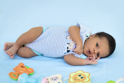 Full-length picture of an infant with his eyes open lying on a blue cloth