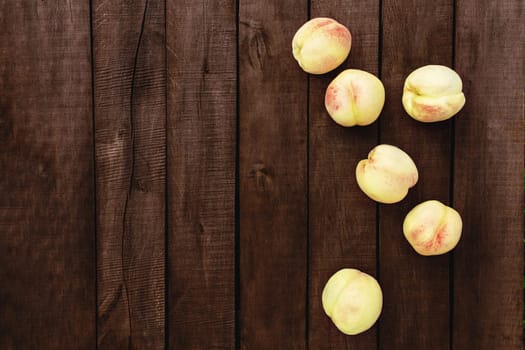 Flat lay with large and big juicy organic peaches group on the brown wooden table background with old boards. Natural fruits, copy space area. High quality photo