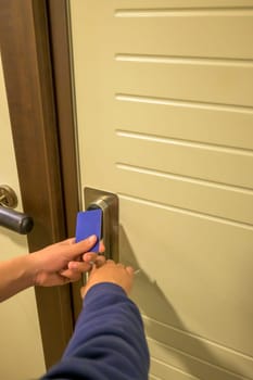 A hand holding a blue card key near a hotel door lock in a long hallway, key electronic lock, hotel room, holidays in mallorca, spain,