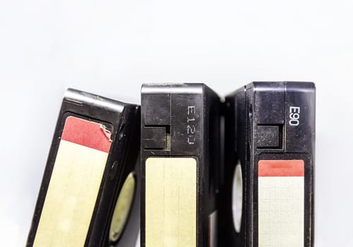 Three VHS video cassettes stacked vertically with blank label isolated on a white background. Past standard video format for home entertainment. Outdated technology.