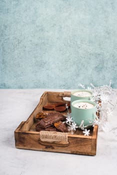 Coffee cups and chocolate coated gingerbread in a wooden basket, empty copy space, christmas season
