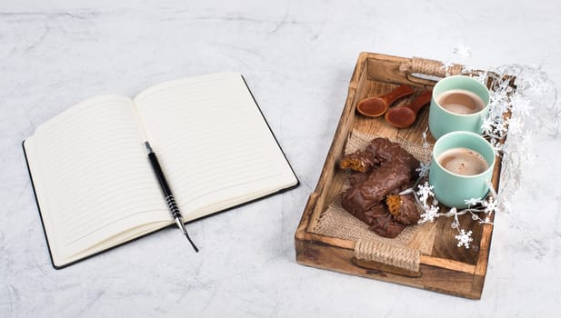 Coffee cups and chocolate coated gingerbread in a wooden basket, empty copy space, christmas season