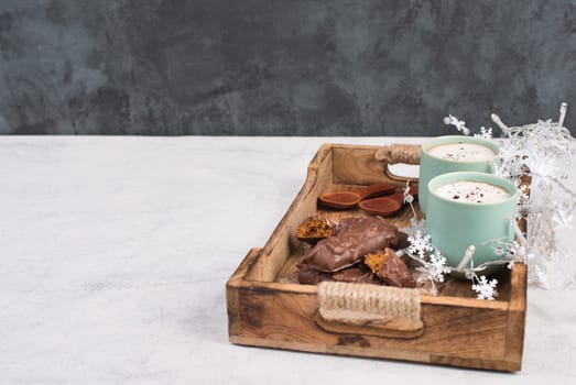 Coffee cups and chocolate coated gingerbread in a wooden basket, empty copy space, christmas season